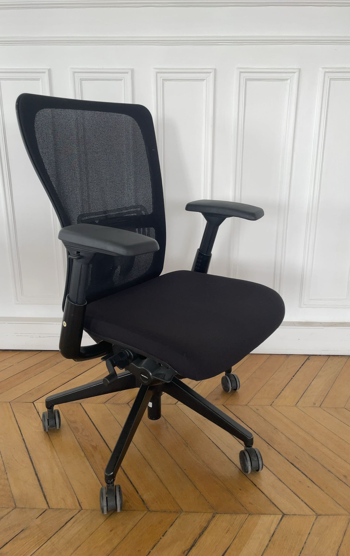 Fauteuil de bureau ergonomique d'occasion avec accoudoirs réglables et dossier en maille.