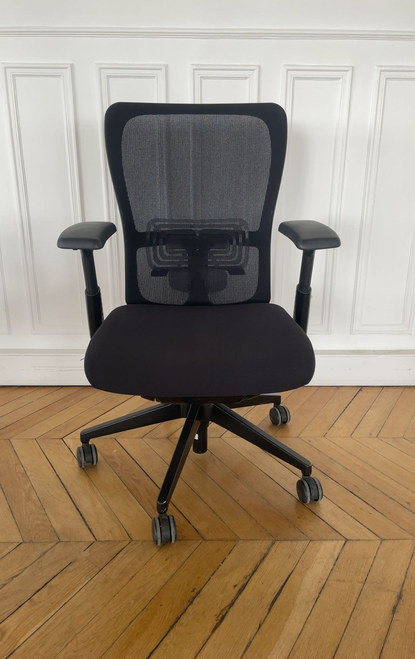 Chaise de bureau reconditionnée avec dossier en maille noire et assise rembourrée.