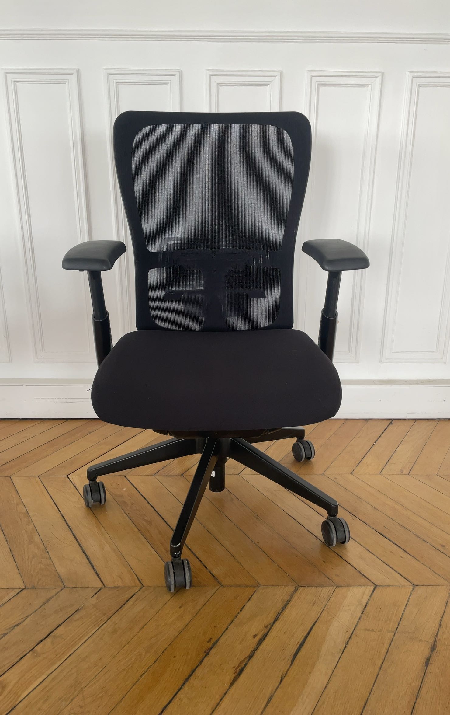 Chaise de bureau reconditionnée avec dossier en maille noire et assise rembourrée.